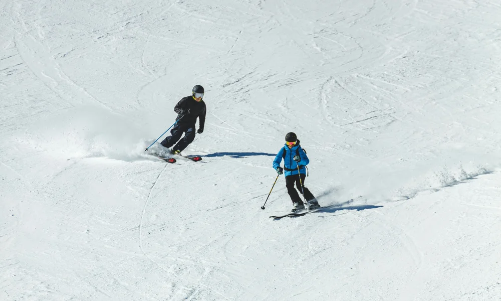 Ferien mit Kindern in Zermatt - Resort La Ginabelle Zermatt Zwei Skifahrer fahren auf schneebedeckter Piste bei Sonnenschein