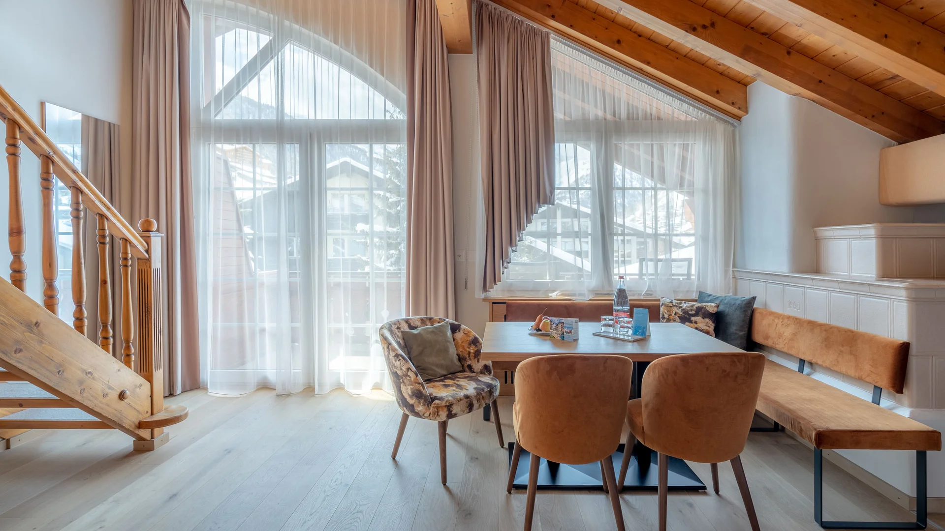 Zimmer, Appartements & Suiten - Resort La Ginabelle Zermatt Essbereich mit modernen Stühlen, Holzbalken und großen Fenstern mit Vorhängen