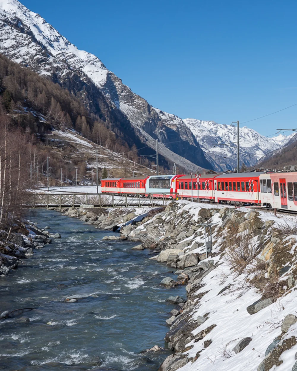 Location & Arrival - Resort La Ginabelle Zermatt Train runs along a river in winter