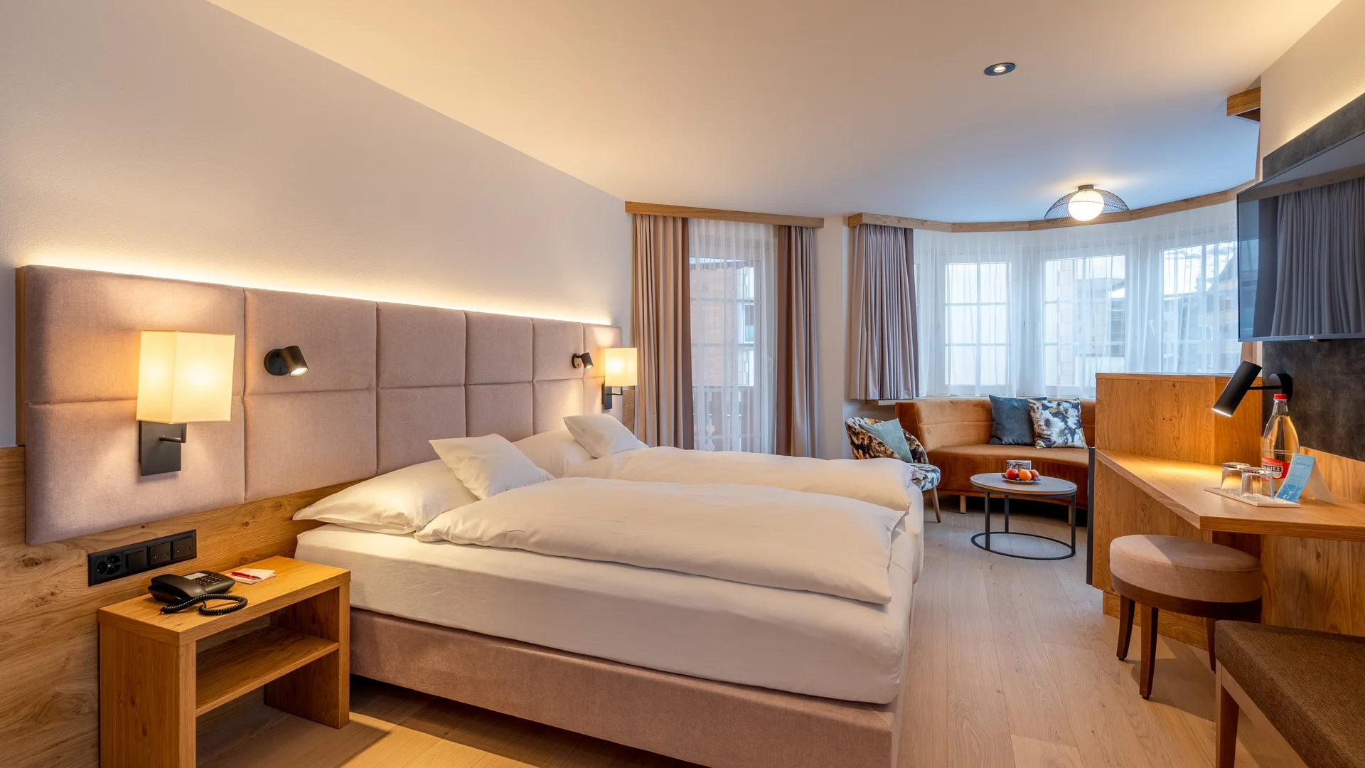 Zimmer, Appartements & Suiten - Resort La Ginabelle Zermatt Hell eingerichtetes Hotelzimmer mit Doppelbett und Sitzbereich