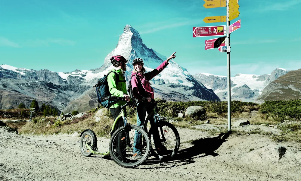 Lage & Anreise nach Zermatt - Resort La Ginabelle Zermatt Zwei Personen auf dem Fahrrad vor dem Matterhorn.