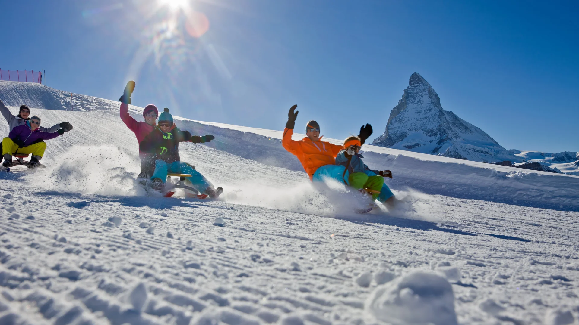 Ferien mit Kindern in Zermatt - Resort La Ginabelle Zermatt Familie am Schlittenfahren bei sonnigem Wetter.