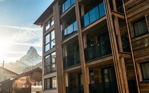 Ferien mit Kindern in Zermatt - Resort La Ginabelle Zermatt Hotelfassade mit Matterhorn und Sonnenuntergang im Hintergrund.