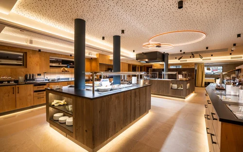 Zimmer, Appartements & Suiten - Resort La Ginabelle Zermatt Frühstücksbuffet mit Holzverkleidung und indirekter Beleuchtung.