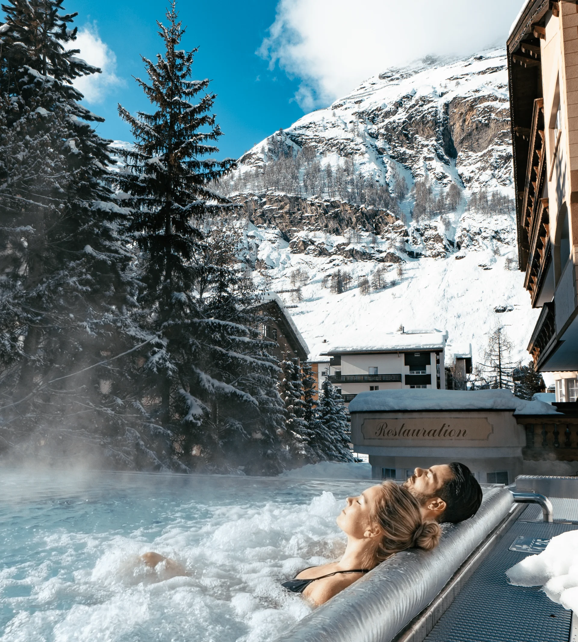 Ferien mit Kindern in Zermatt - Resort La Ginabelle Zermatt Menschen im Infinitypool mit Massagedüsen und Aussicht auf die verschneiten Berge im Winter.