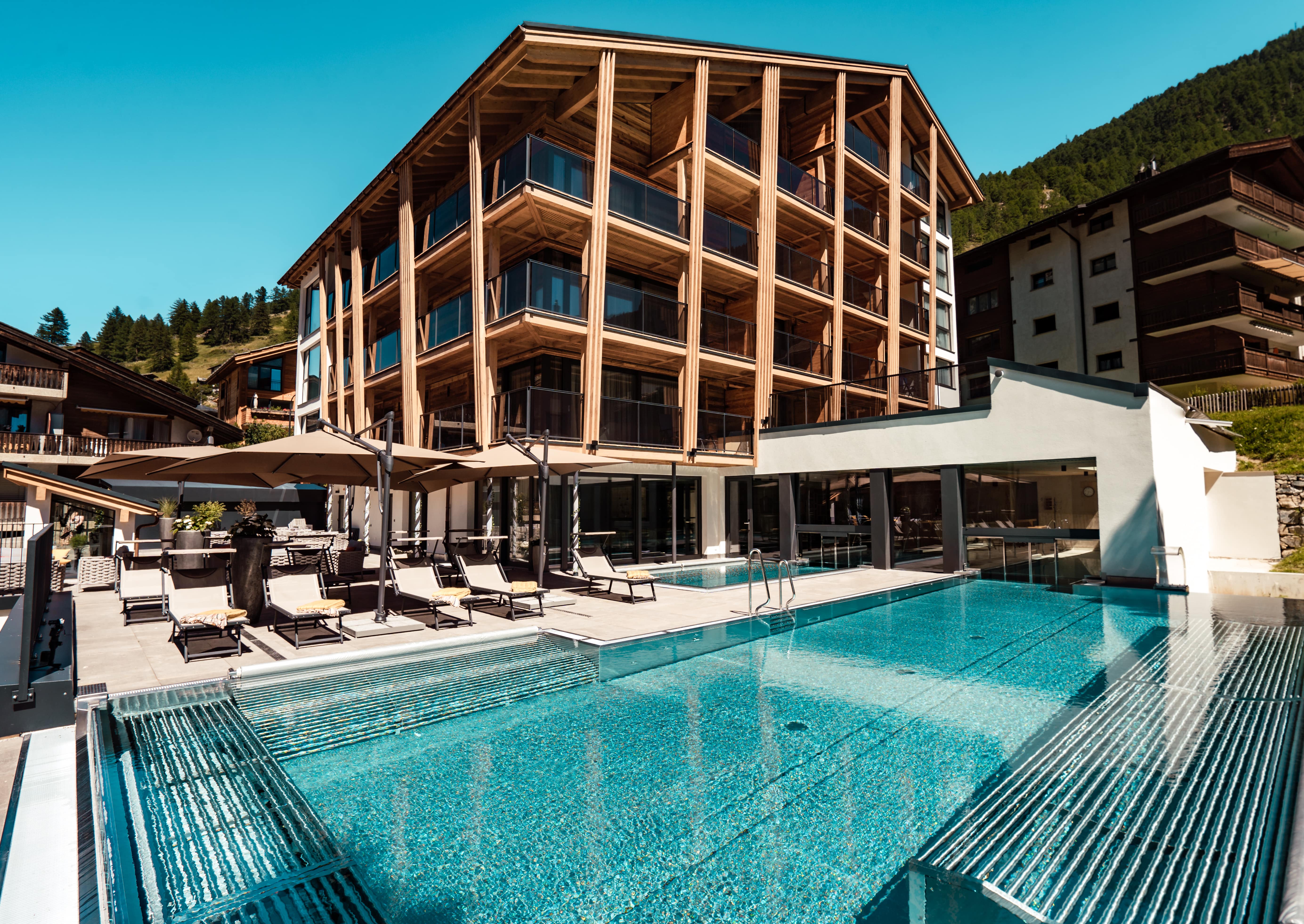 Ferien mit Kindern in Zermatt - Resort La Ginabelle Zermatt Hotel mit Infinitypool und Terrasse im Sommer.