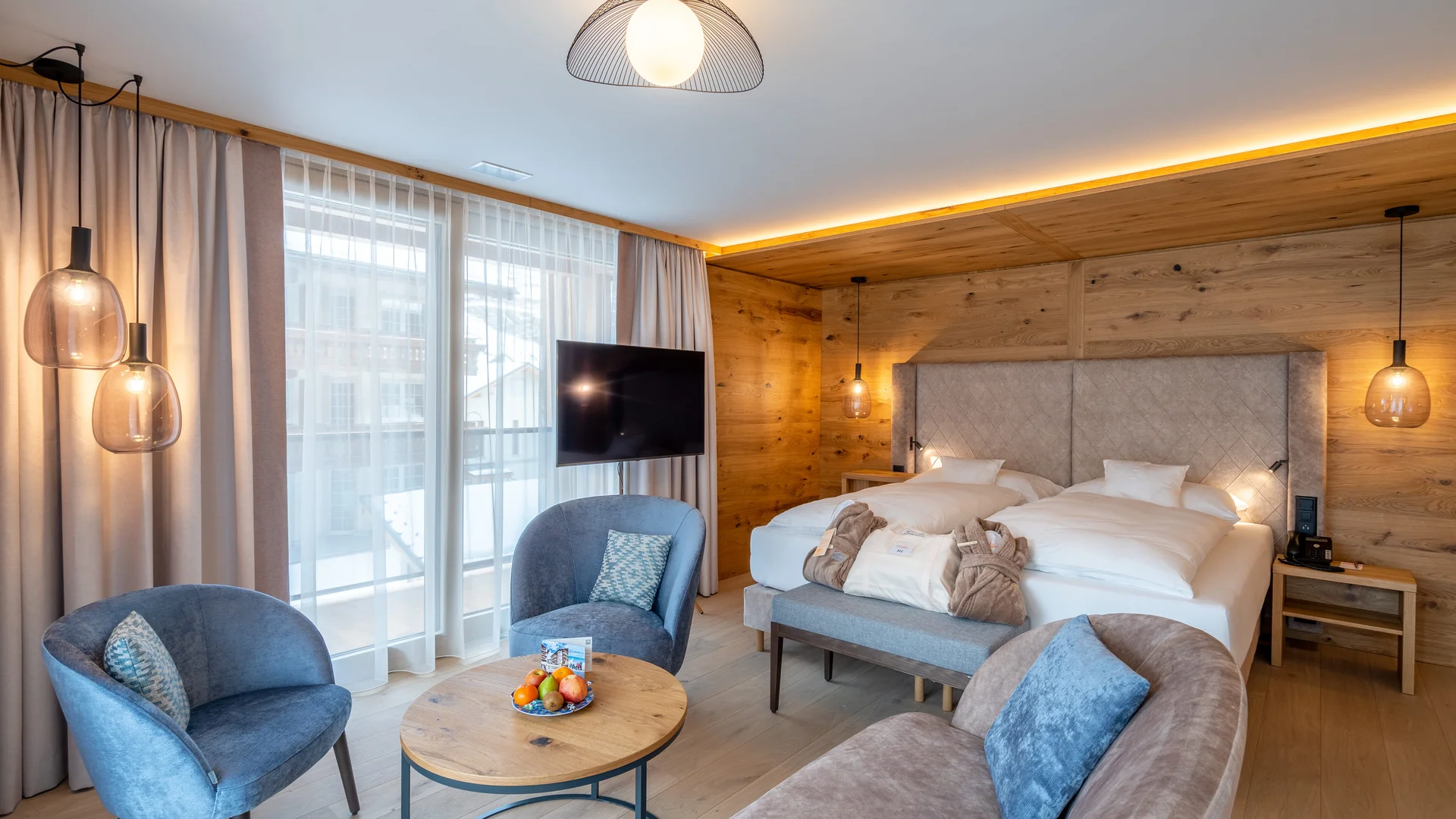 Resort La Ginabelle Zermatt: Ihr 4*S Wellnessresort in Zermatt Modernes Zimmer mit Bett im Hintergrund und Sitzgruppe im Vordergrund.
