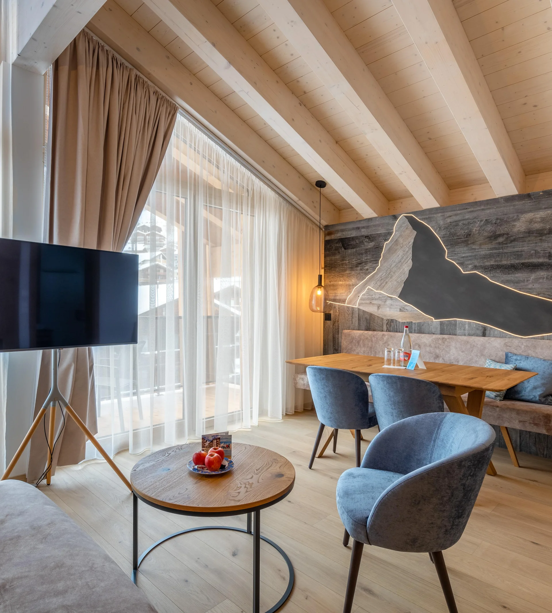 Resort La Ginabelle Zermatt: Ihr 4*S Wellnessresort in Zermatt Wohnbereich des Appartements mit TV und beleuchtetem Matterhorn aus Holz