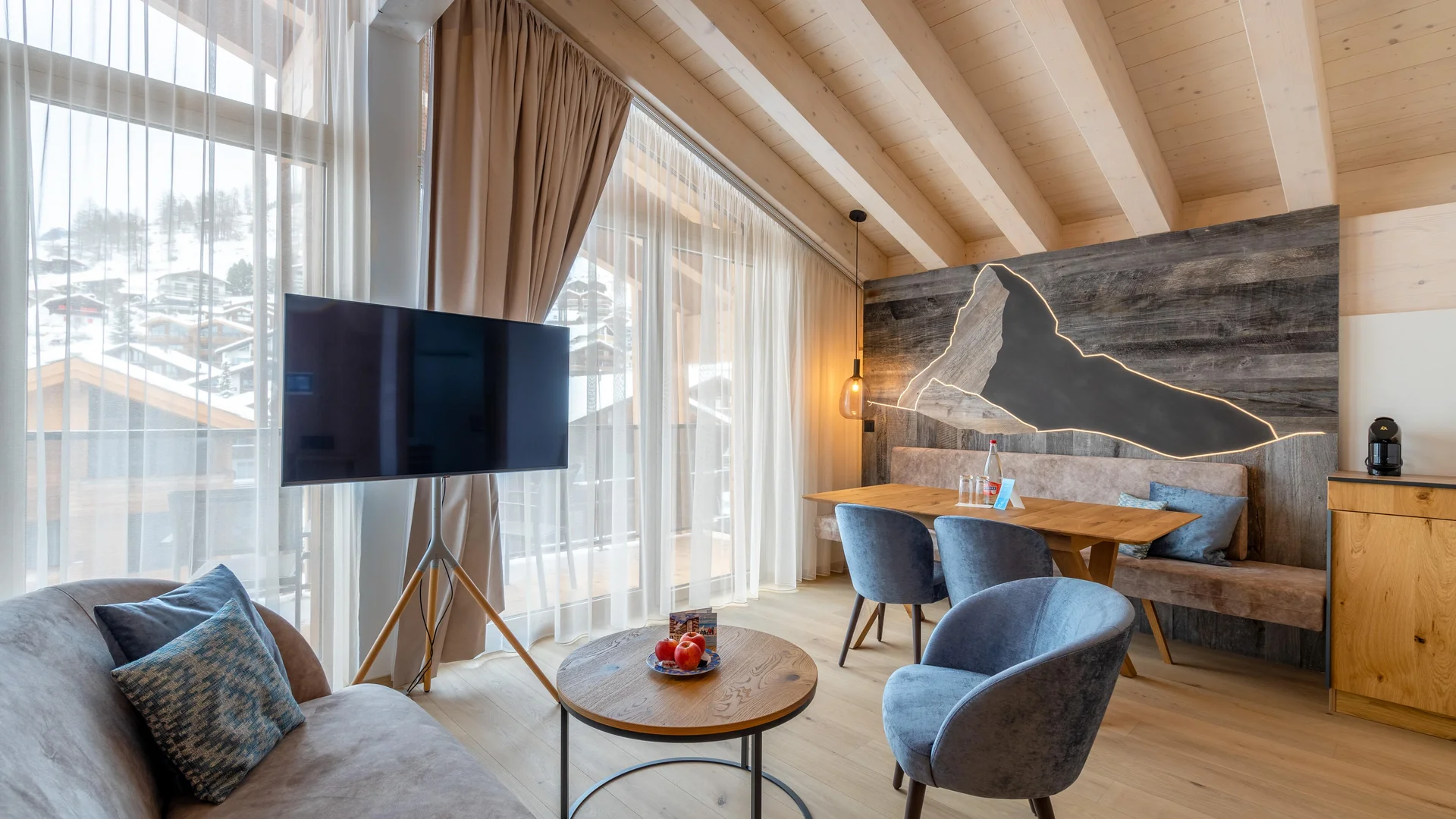 Resort La Ginabelle Zermatt: Ihr 4*S Wellnessresort in Zermatt Wohnbereich des Appartements mit TV und beleuchtetem Matterhorn aus Holz