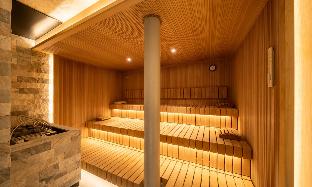 Resort La Ginabelle Zermatt: Ihr 4*S Wellnessresort in Zermatt Moderner Holzsauna mit beleuchteten Bänken und Steinofen