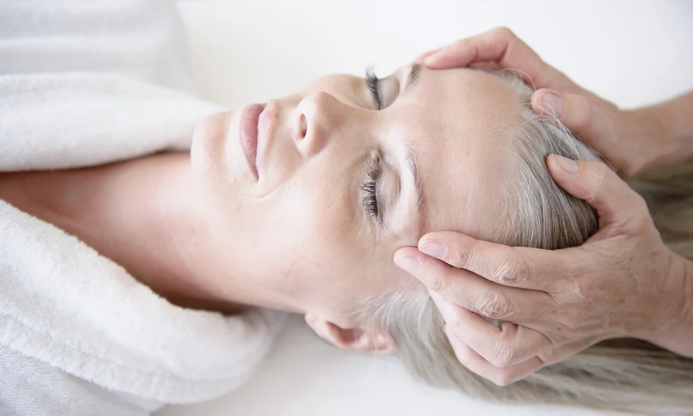 Wellnesshotel in Zermatt | GinaSPA im Resort La Ginabelle Eine entspannte Frau erhält eine Kopfmassage.
