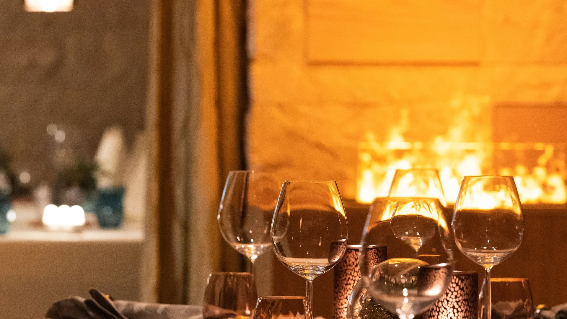 Resort La Ginabelle Zermatt: Ihr 4*S Wellnessresort in Zermatt Gedeckte Tische im Restaurant mit stimmungsvollem Kamin im Hintergrund