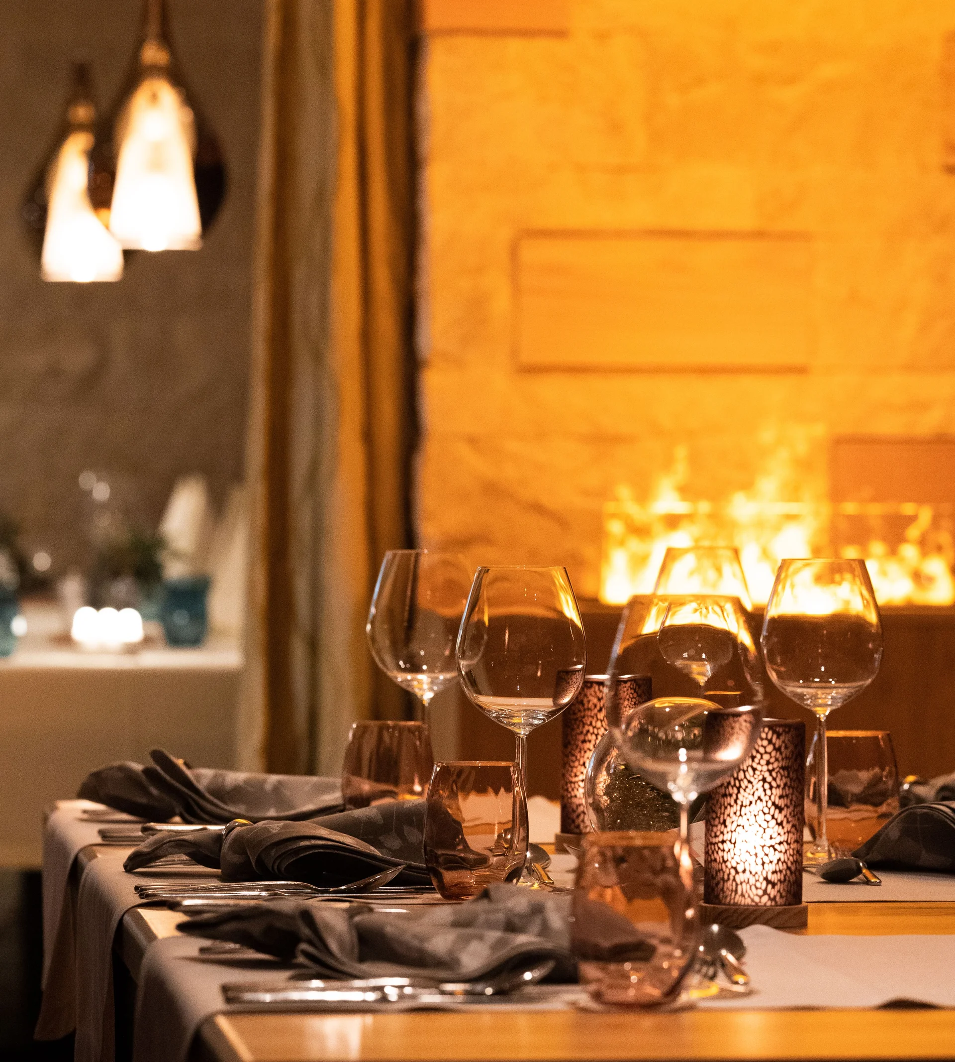 Resort La Ginabelle Zermatt: Ihr 4*S Wellnessresort in Zermatt Gedeckte Tische im Restaurant mit stimmungsvollem Kamin im Hintergrund