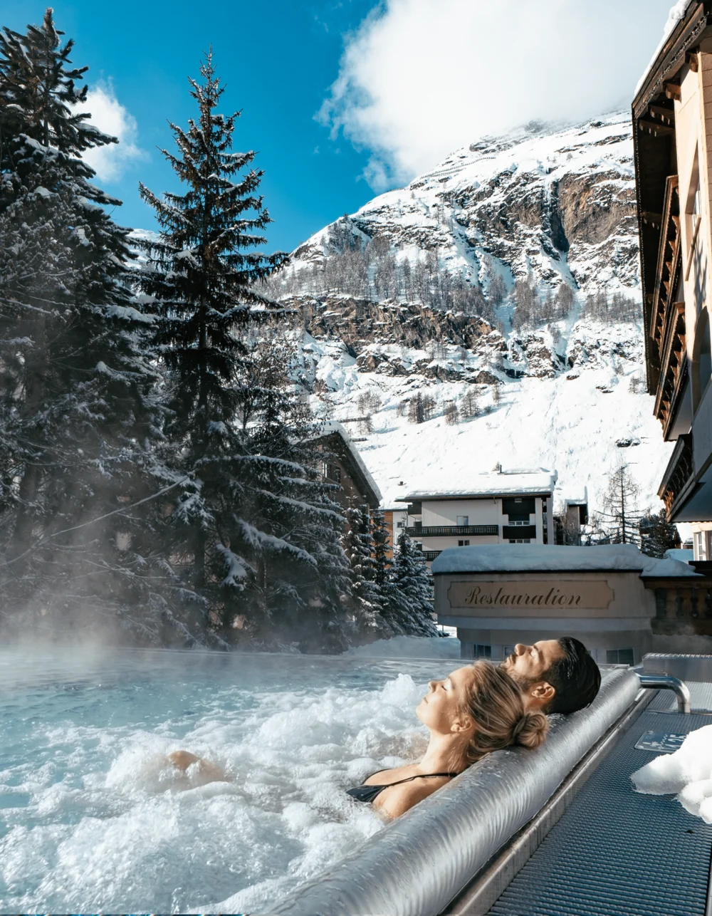 Resort La Ginabelle Zermatt: Ihr 4*S Wellnessresort in Zermatt Menschen im Infinitypool mit Massagedüsen und Aussicht auf die verschneiten Berge im Winter.