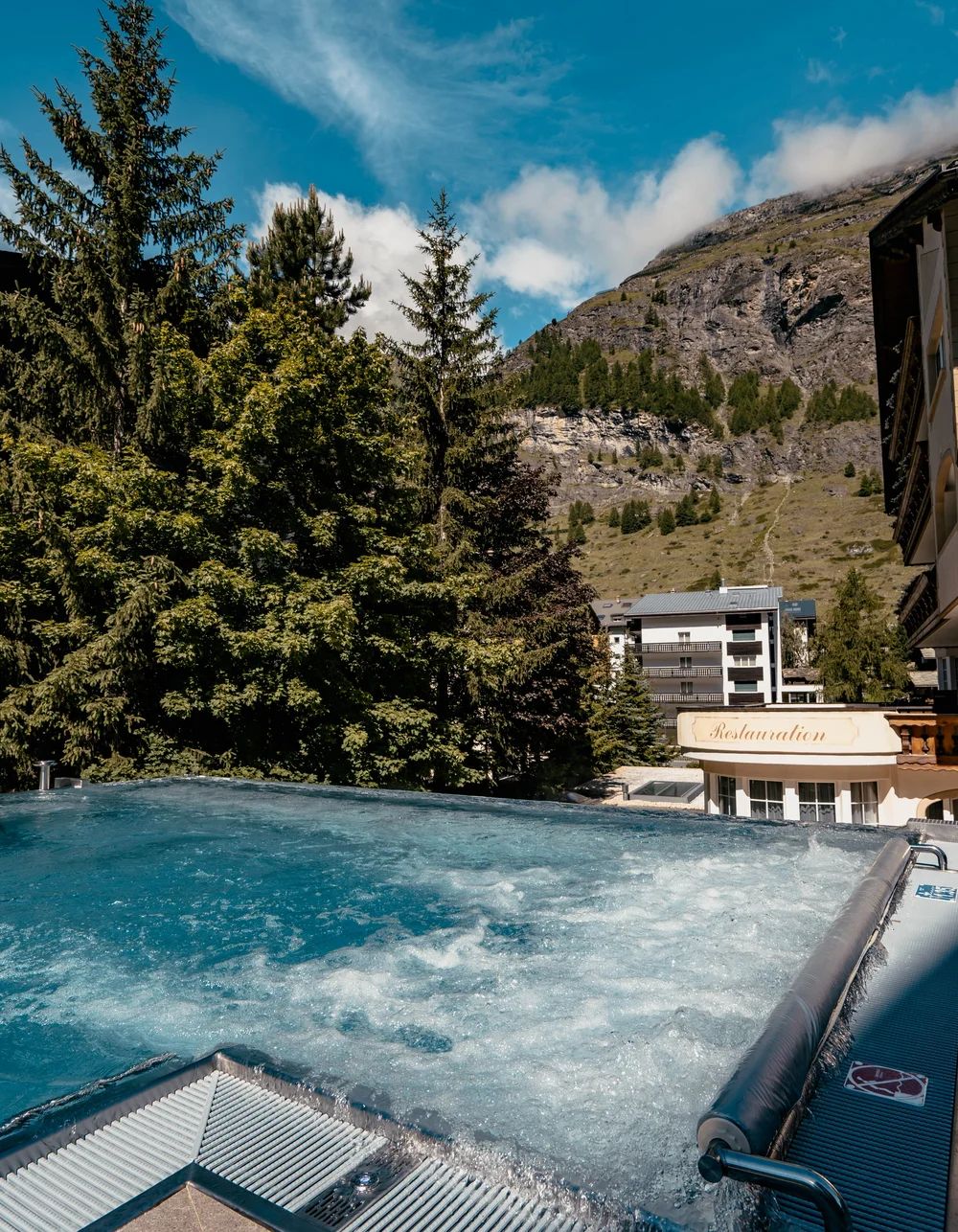 Resort La Ginabelle Zermatt: Ihr 4*S Wellnessresort in Zermatt Infinitypool mit Massagedüsen und Aussicht auf die Berge im Sommer.